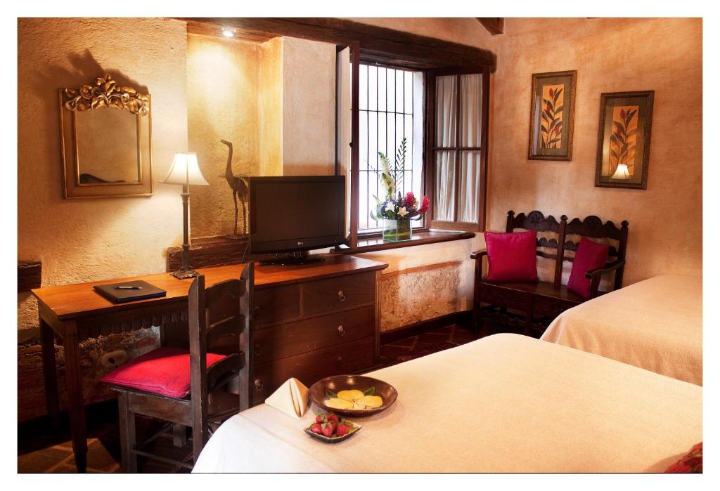 a hotel room with a desk and a television at Meson de Maria in Antigua Guatemala