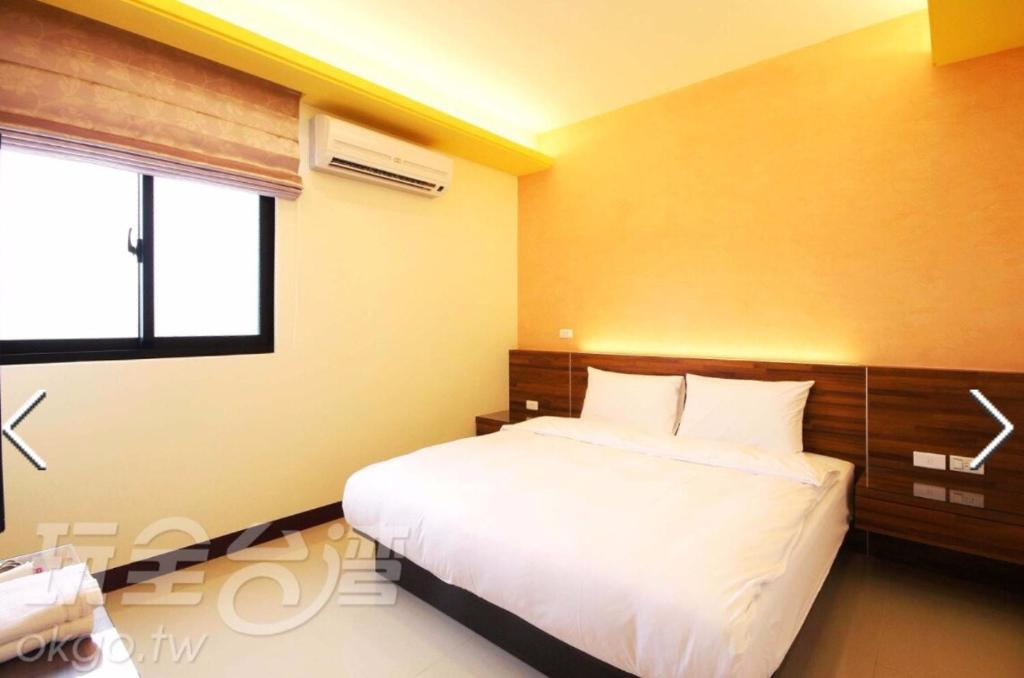- une chambre avec un lit blanc et une fenêtre dans l'établissement Here B&B, à Magong