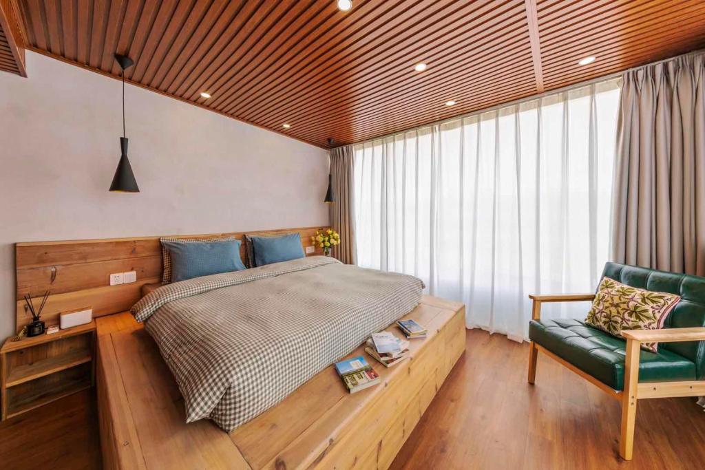 a bedroom with a large bed and a green chair at U shore house in Quanzhou