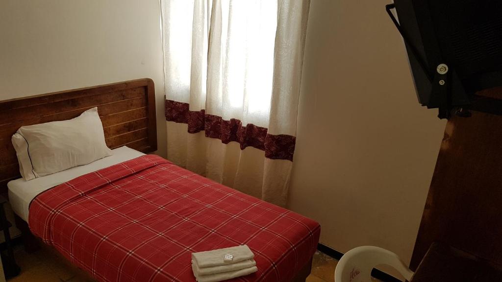 1 dormitorio con cama roja y ventana en Departamento 7/7, en Tlaxcala de Xicohténcatl