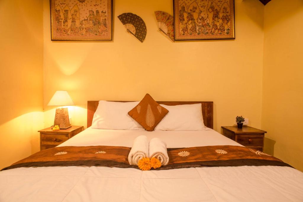 ein Schlafzimmer mit einem Bett mit zwei Nachttischen und zwei Lampen in der Unterkunft Kamar Suci House in Ubud