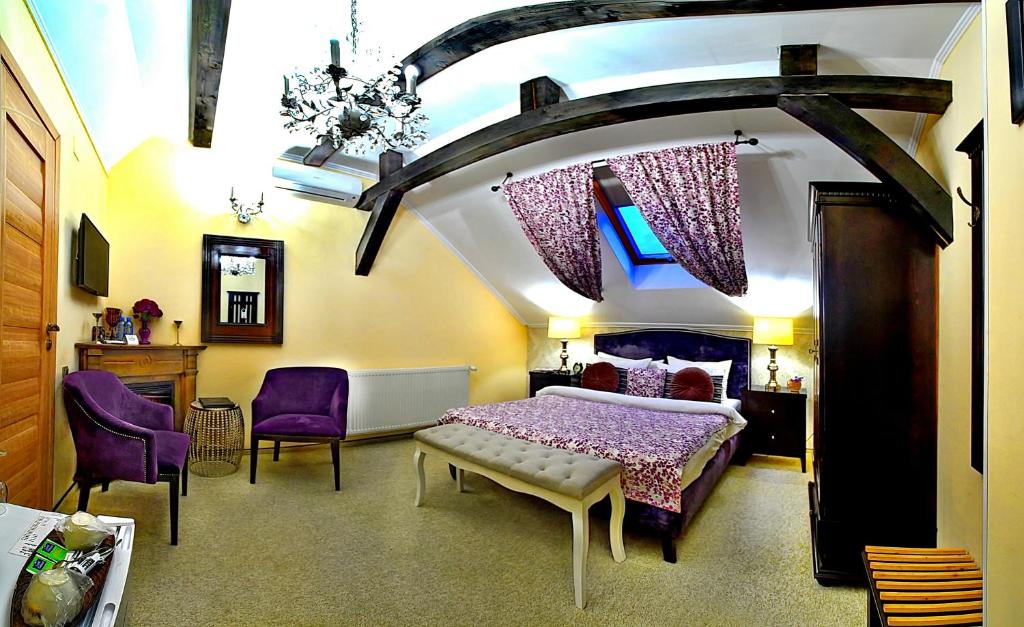 a bedroom with a large bed and purple chairs at Vila SaraDa Boutique in Deva