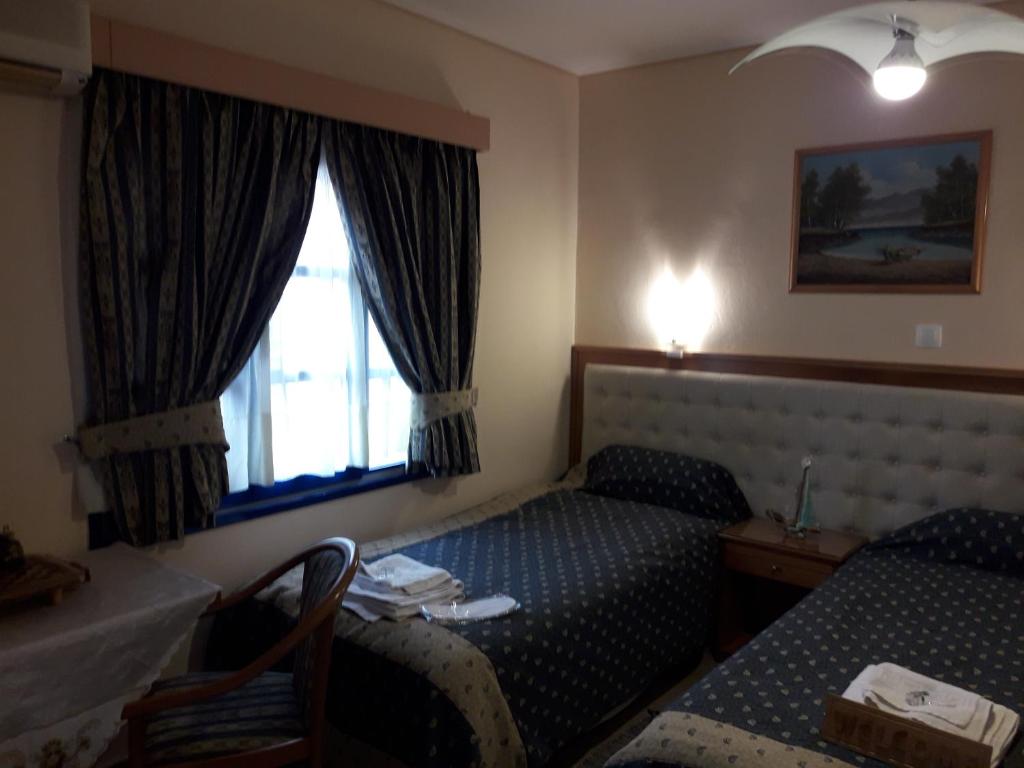 um quarto de hotel com duas camas e uma janela em Studios Cosmopolitan em Panagioúda