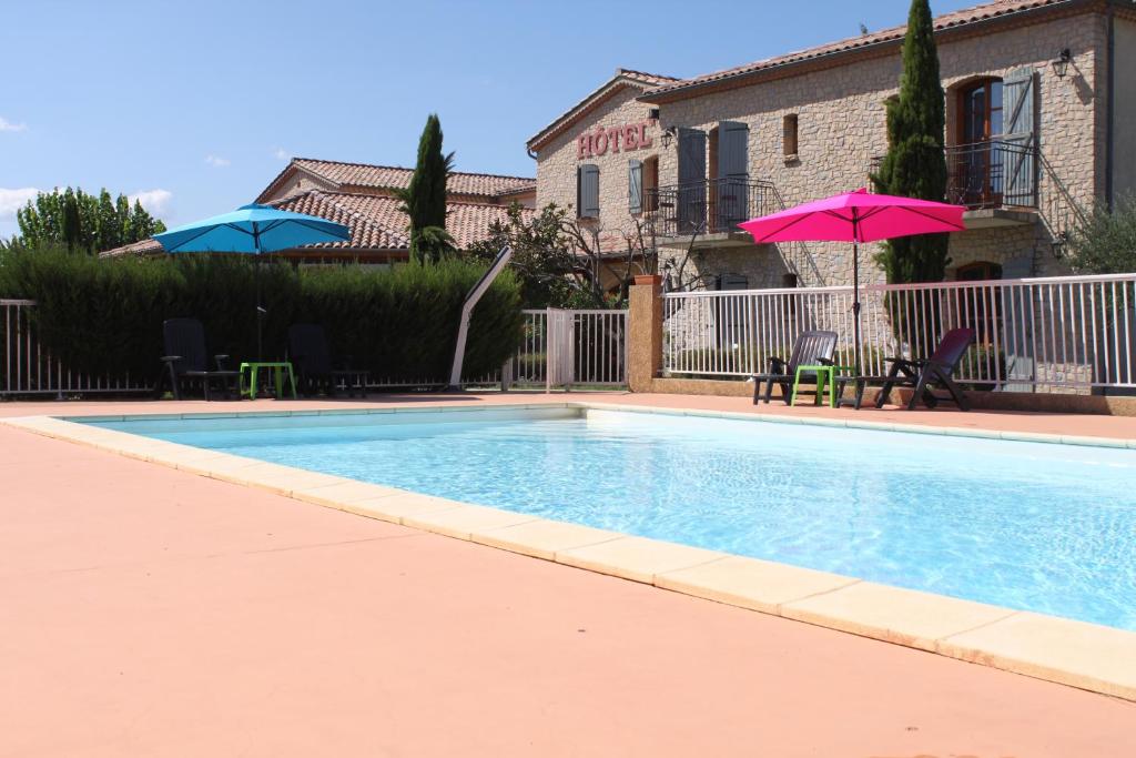 - une piscine avec un parasol et des chaises roses dans l'établissement Logis Hôtel Restaurant Le Mas de Mon Père, à Saint-Jean-le-Centenier