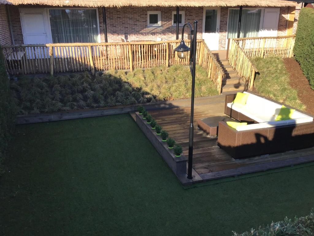 a backyard with a deck with a bench and a lawn at VAKANTIE WONING OASE in Breskens