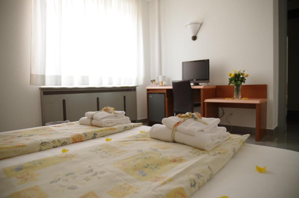 two beds with towels on them in a room at Hotel Bahnhof Haus in Chiasso