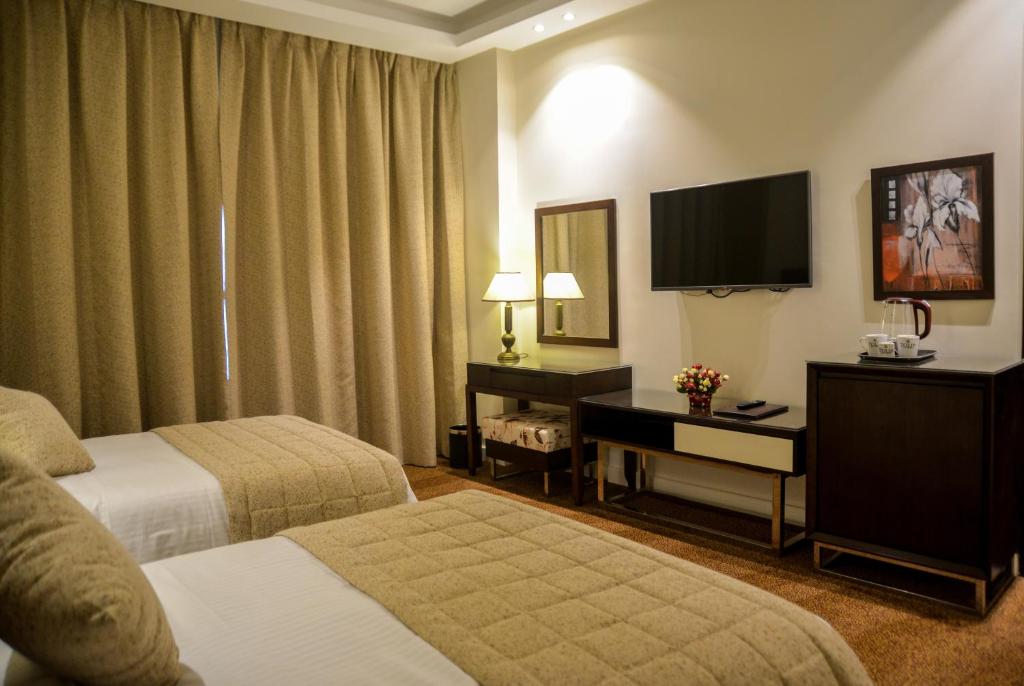 a hotel room with two beds and a flat screen tv at Tolip El Narges in Cairo