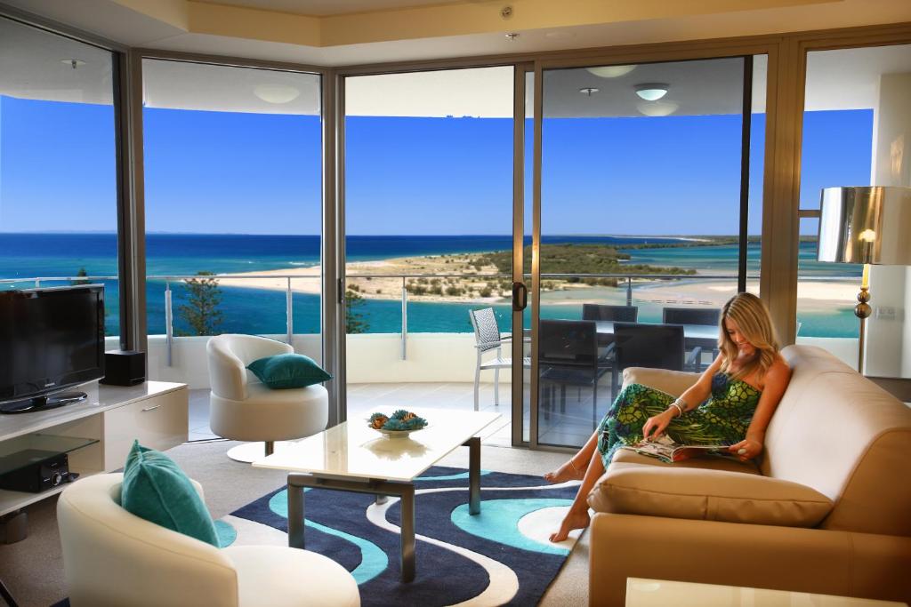 a woman sitting on a couch in a living room at Monaco Caloundra in Caloundra