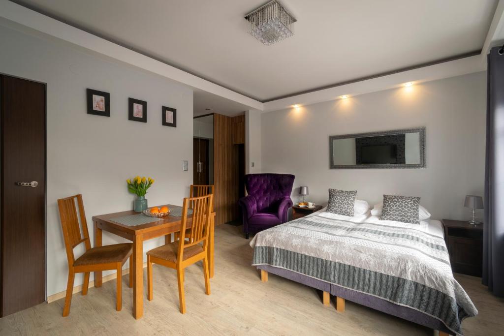 a bedroom with a bed and a table and a chair at Apartament SZEROKA in Gdańsk