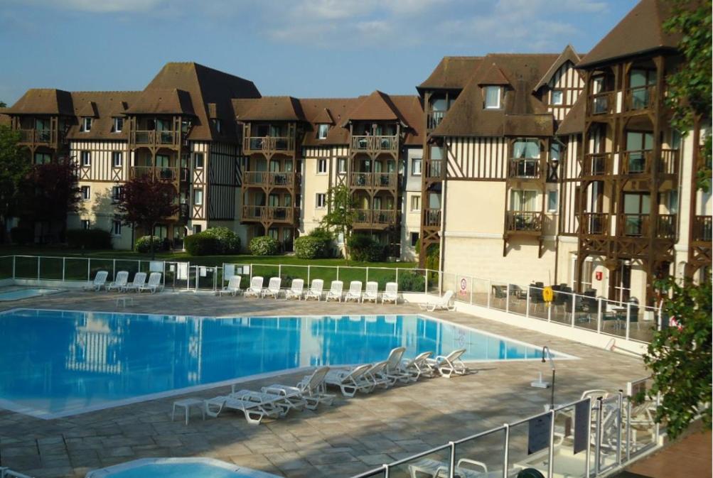 una gran piscina con sillas y algunos edificios en TRES BEL APPARTEMENT 8 PERSONNES WIFI OFFERT en Deauville