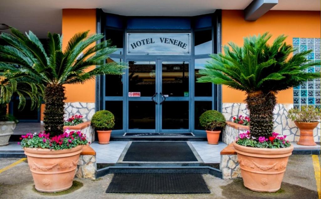 una puerta delantera de un hotel con palmeras y flores en Hotel Venere en Villaricca