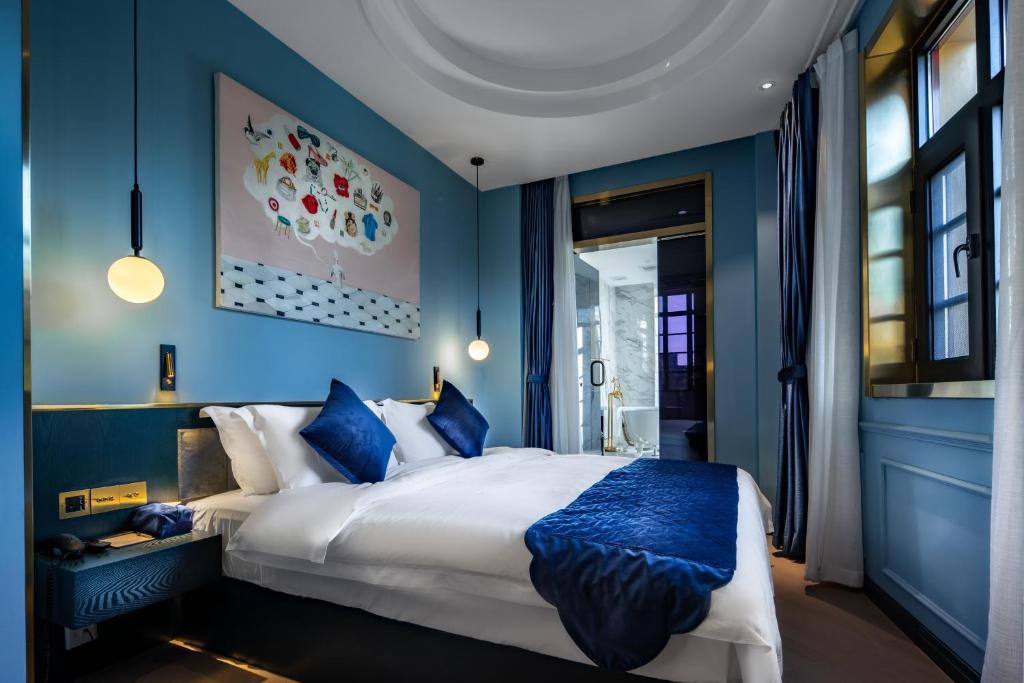 a blue bedroom with a large bed with blue walls at Moon and Chalice Boutique Hotel in Kunming