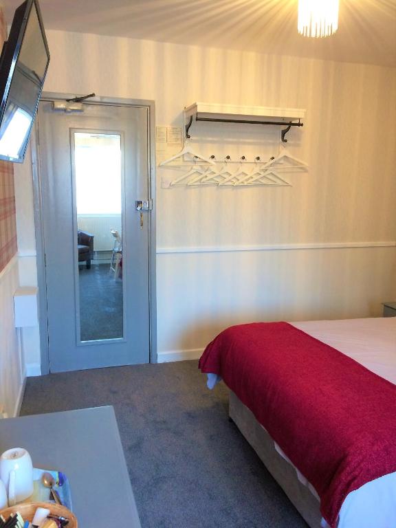 a bedroom with a bed with a red blanket and a window at Lewinsdale Lodge in Weston-super-Mare