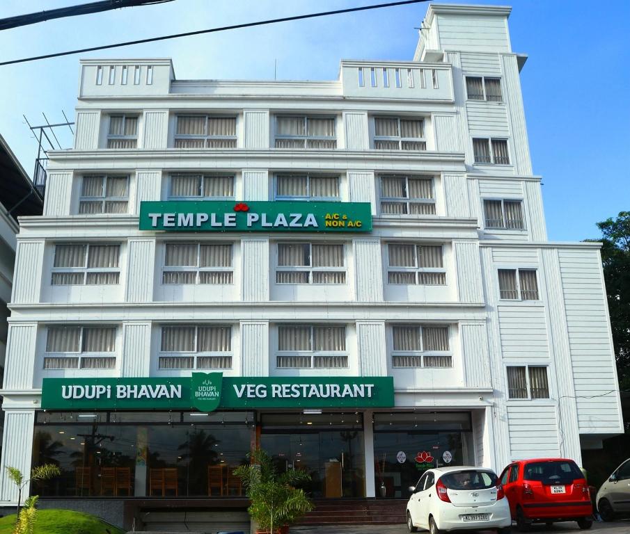 un edificio blanco con coches estacionados frente a él en Temple Plaza Kochi, en Chottanikara