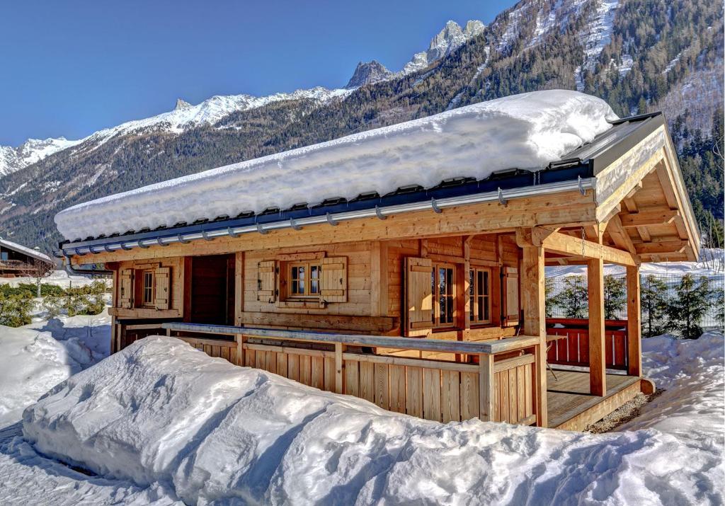 una cabaña de madera en la nieve con una montaña en Chalets Ile des Barrats, en Chamonix-Mont-Blanc