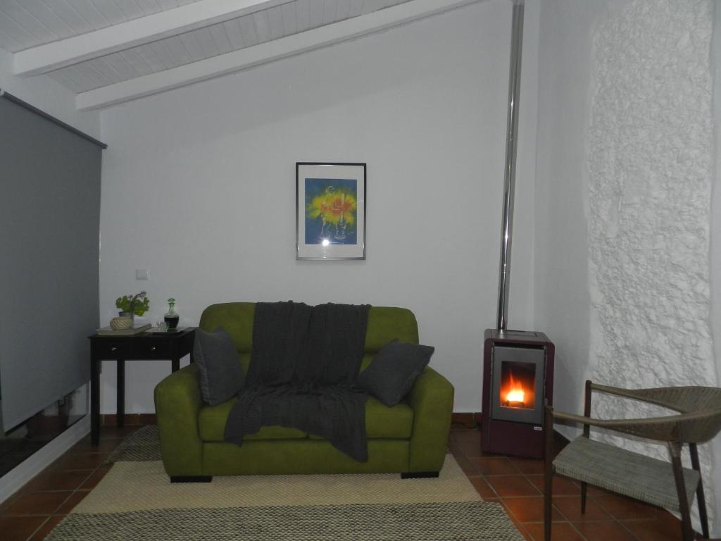 um sofá verde numa sala de estar com lareira em Casas do Ardila em Santo Amador