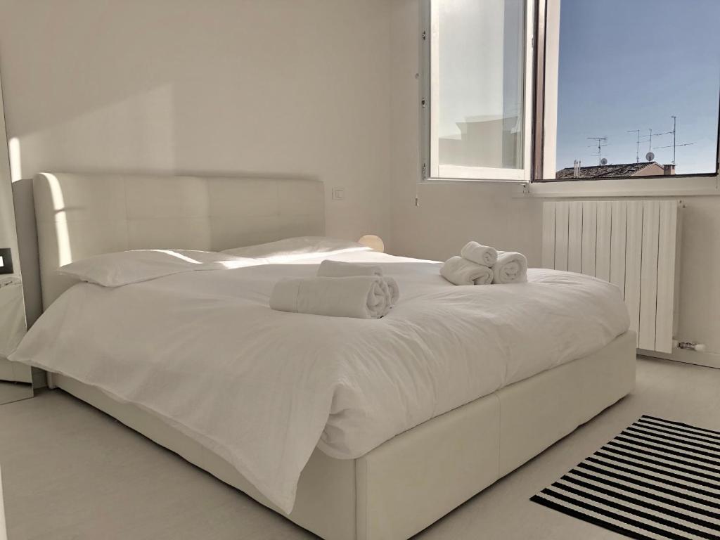 Una cama blanca con toallas en un dormitorio en Appartamento SAN MICHELE, en Verona