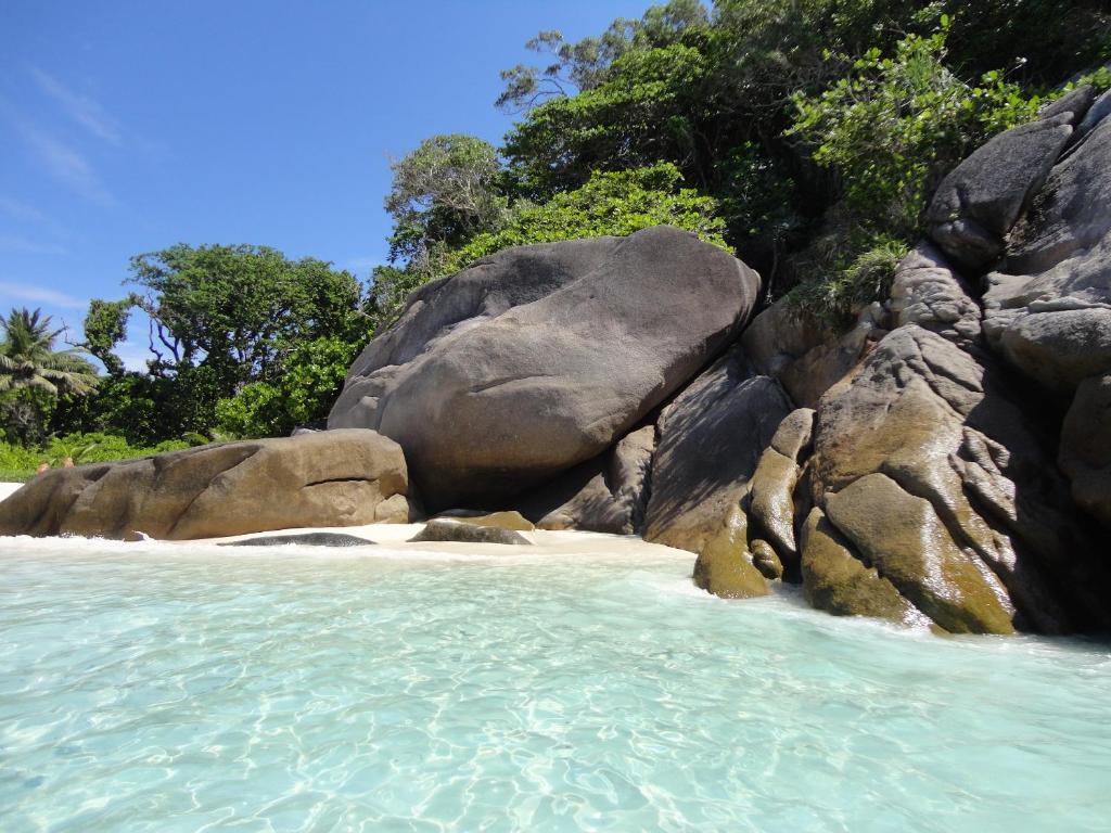 a rocky beach with blue water and rocks at The Sarojin in Khao Lak