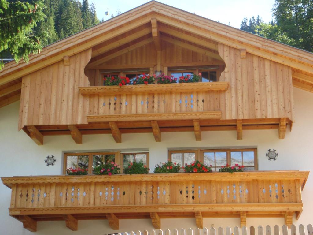 a house with a balcony with flowers on it at Appartamenti Col da Vënt in Corvara in Badia