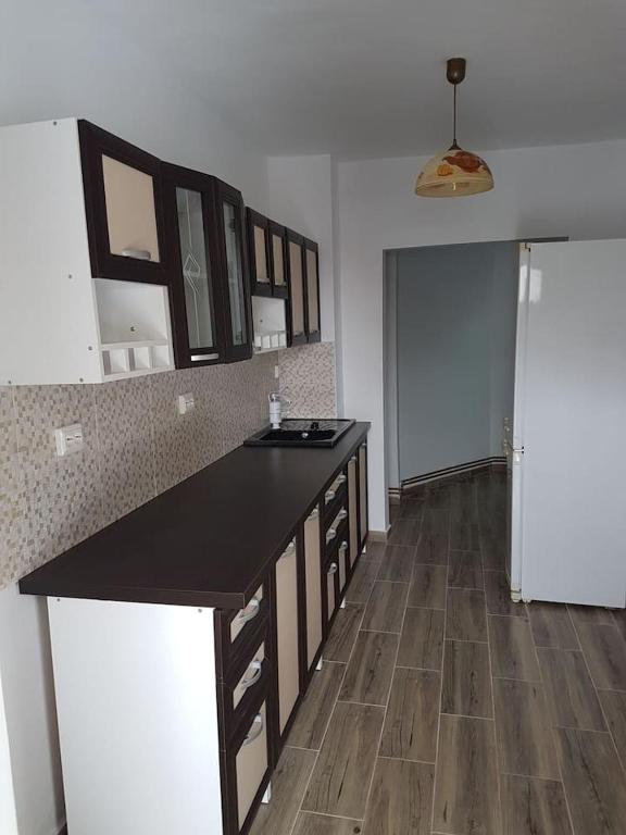 a kitchen with a black counter and a wooden floor at Apartament Mioritza 2A in Horezu