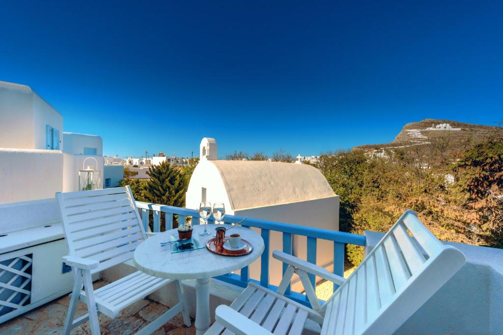 a balcony with white chairs and a table and a view at Chora Resort Hotel & Spa in Chora Folegandros