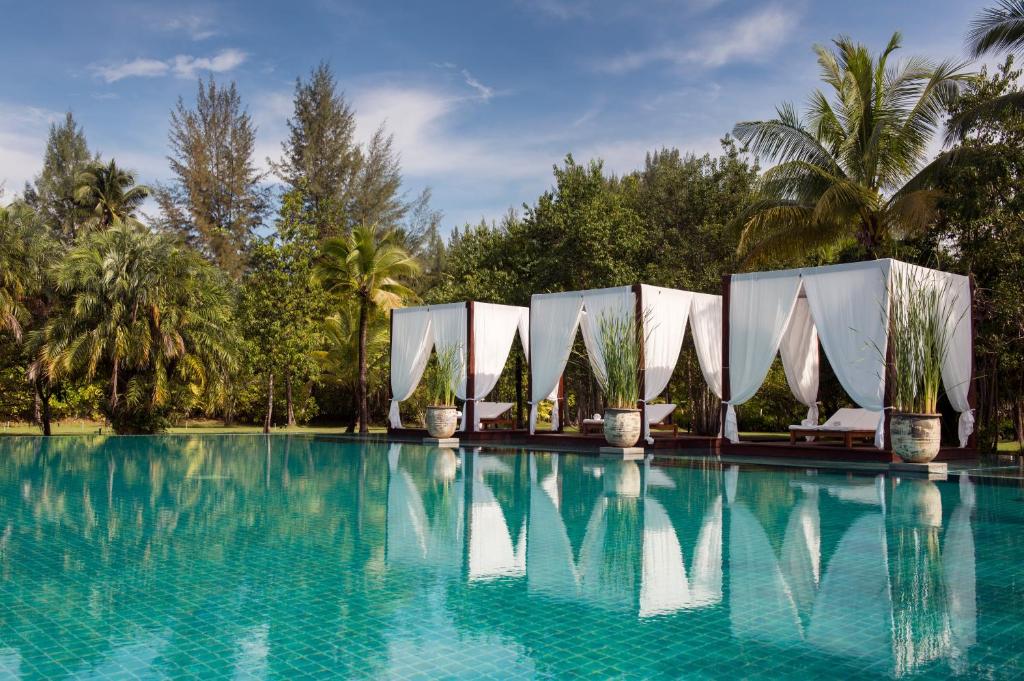 uma piscina num resort com árvores ao fundo em The Sarojin em Khao Lak