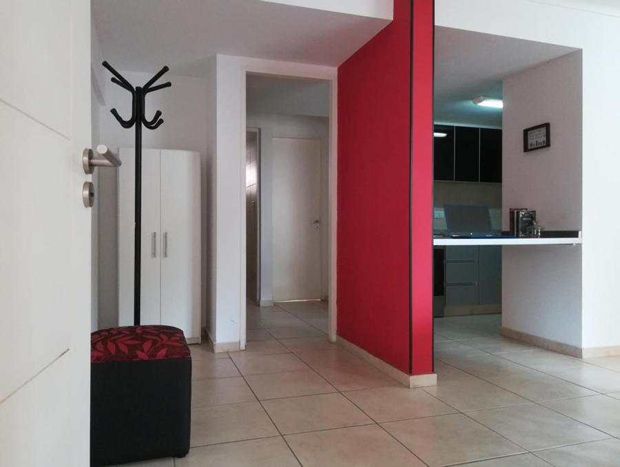 sala de estar con pared roja y cocina en Departamento Sol Cuyano en Mendoza