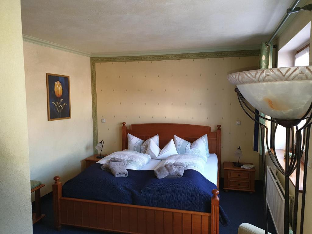 a bedroom with a blue bed with two pillows at Hotel Piccolo in Schleiz