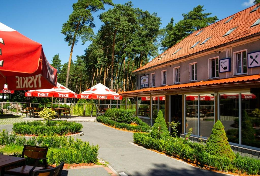 a building with red umbrellas and tables and chairs at Ani Pensjonat in Borne Sulinowo