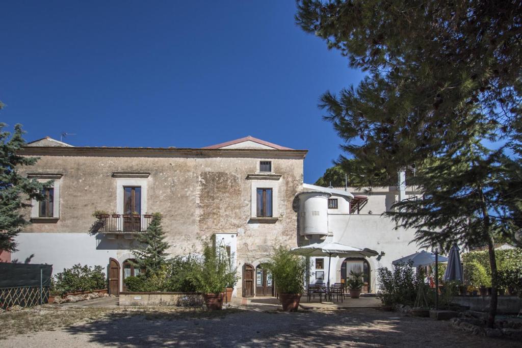 een groot stenen huis met een boom ervoor bij MASSERIA CITULO Il Pino grande in Castel del Monte