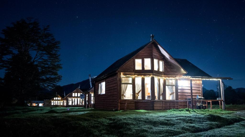 a large wooden house with lights on it at night at Cabañas Shangrila Aysen in Puerto Aisén