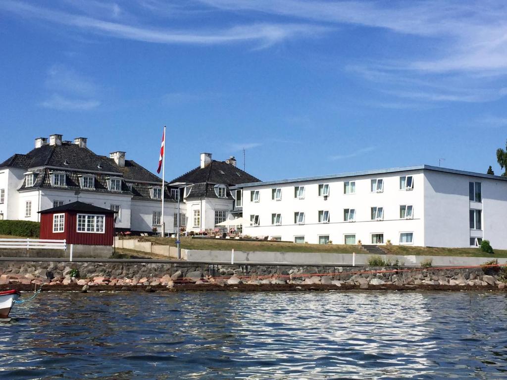 a large white building next to a body of water at Hotel Udsigten Marstal in Marstal