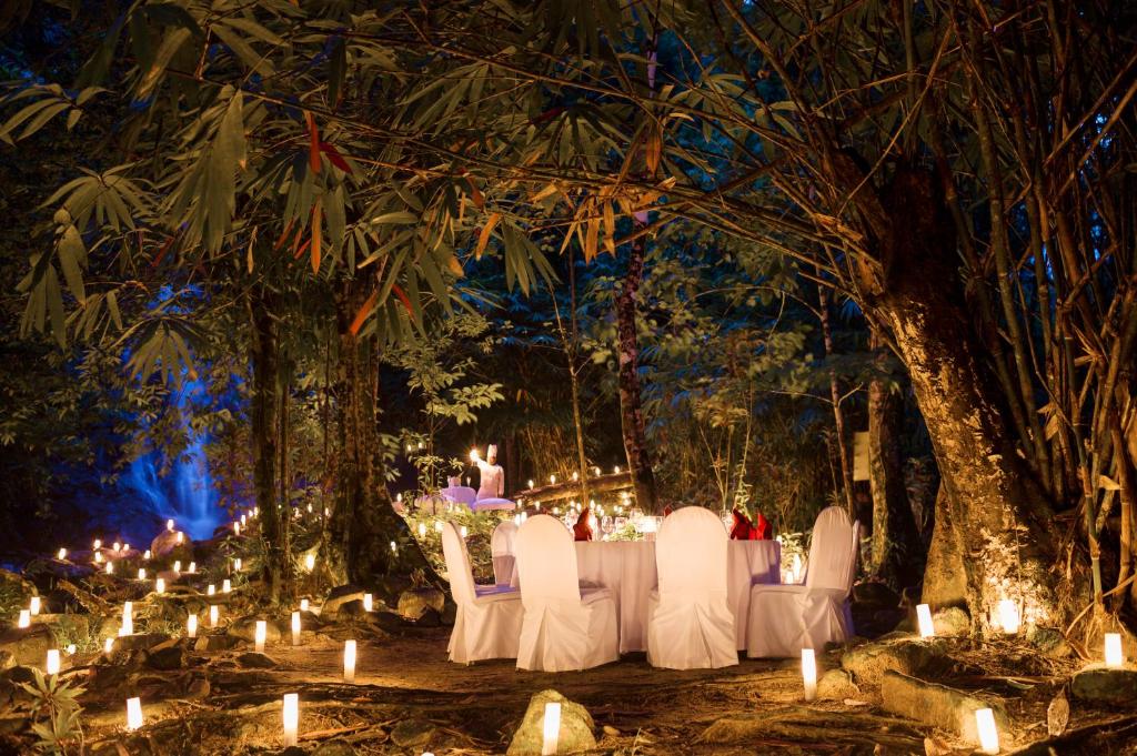 a table with white chairs and candles in a forest at The Sarojin in Khao Lak