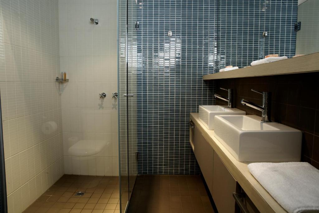 a bathroom with two sinks and a glass shower at Best Western Melbourne City in Melbourne