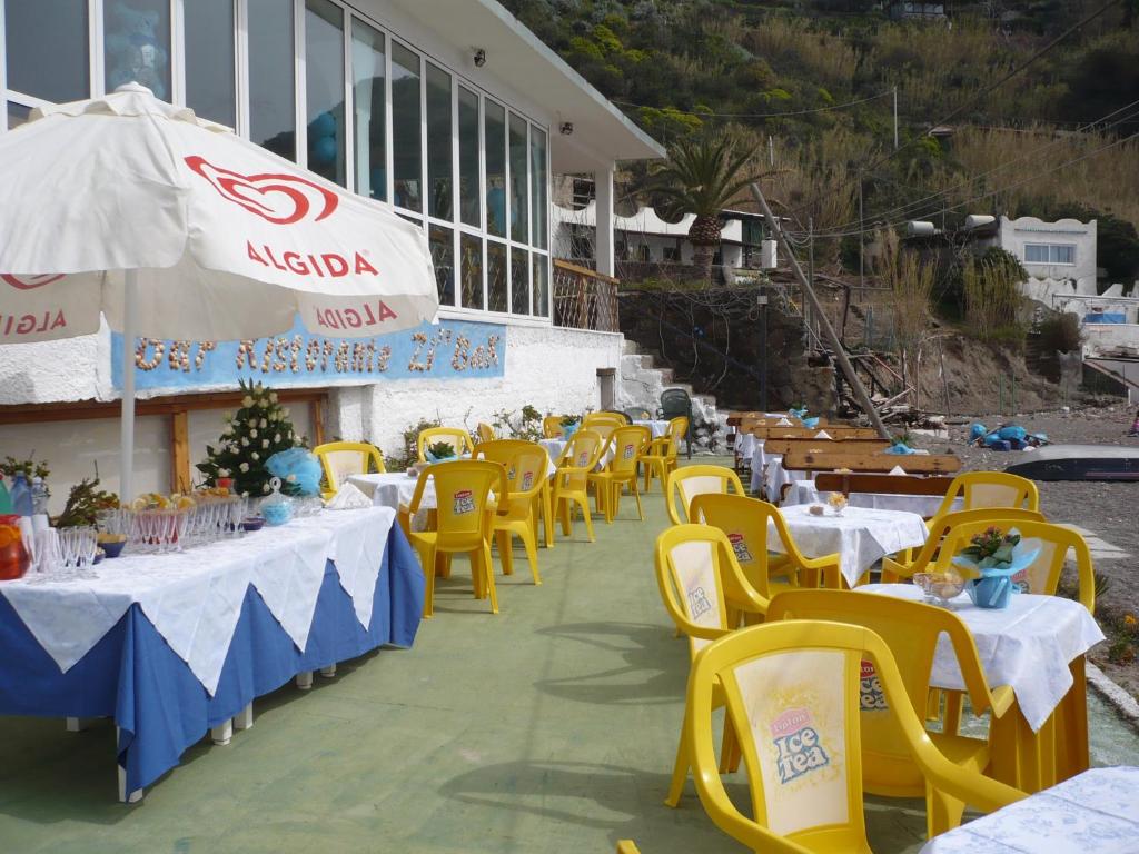 een rij tafels met gele stoelen en een paraplu bij Zi Bak in Ischia