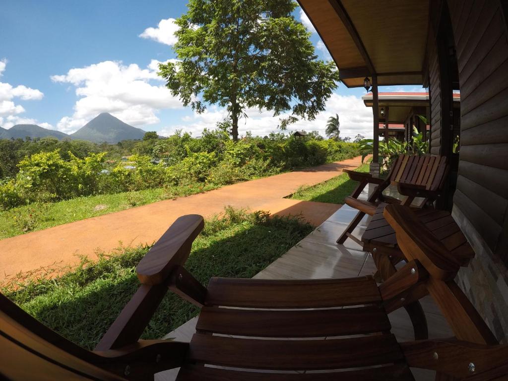 a porch with wooden chairs and a dirt road at Cabañas Sueños del Arenal in Fortuna