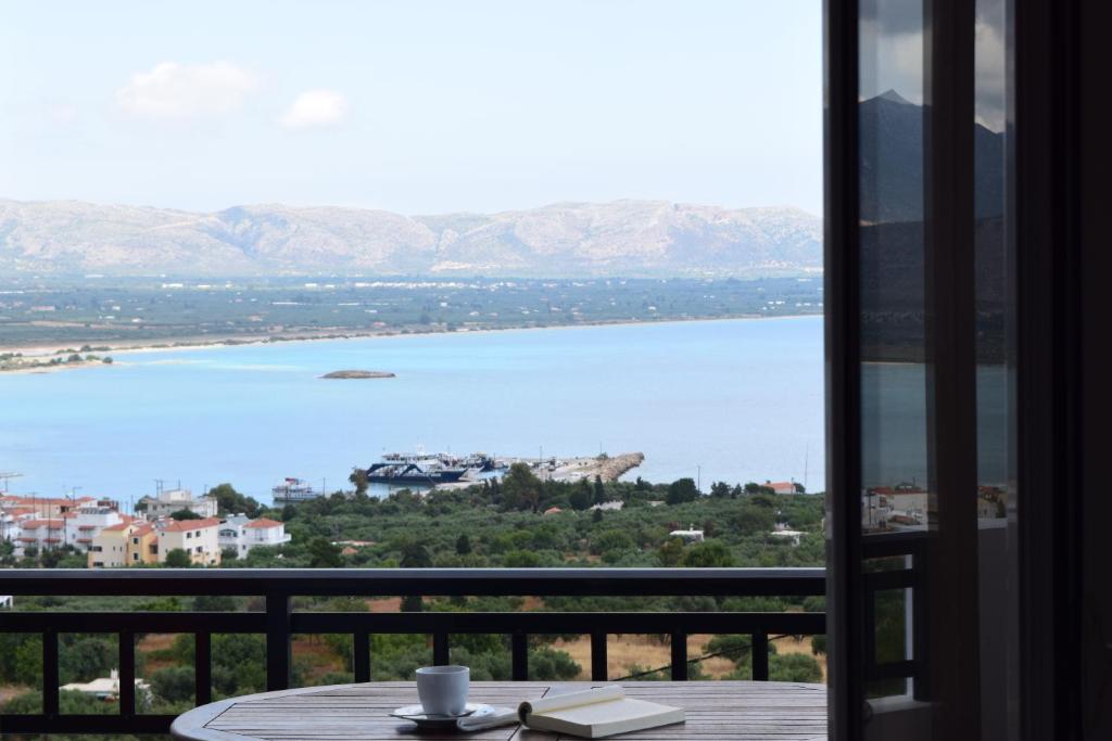 een tafel met een kopje koffie op een balkon met uitzicht op een meer bij Studios Maniati in Elafonisos