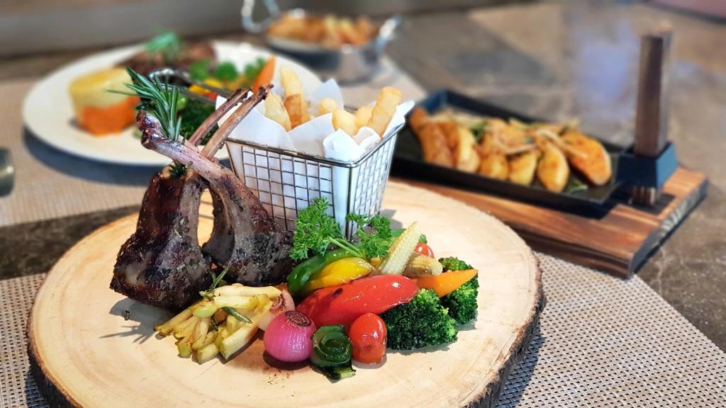 a plate of food with meat and vegetables on a table at Aurico Kata Resort & Spa - SHA Extra Plus in Kata Beach