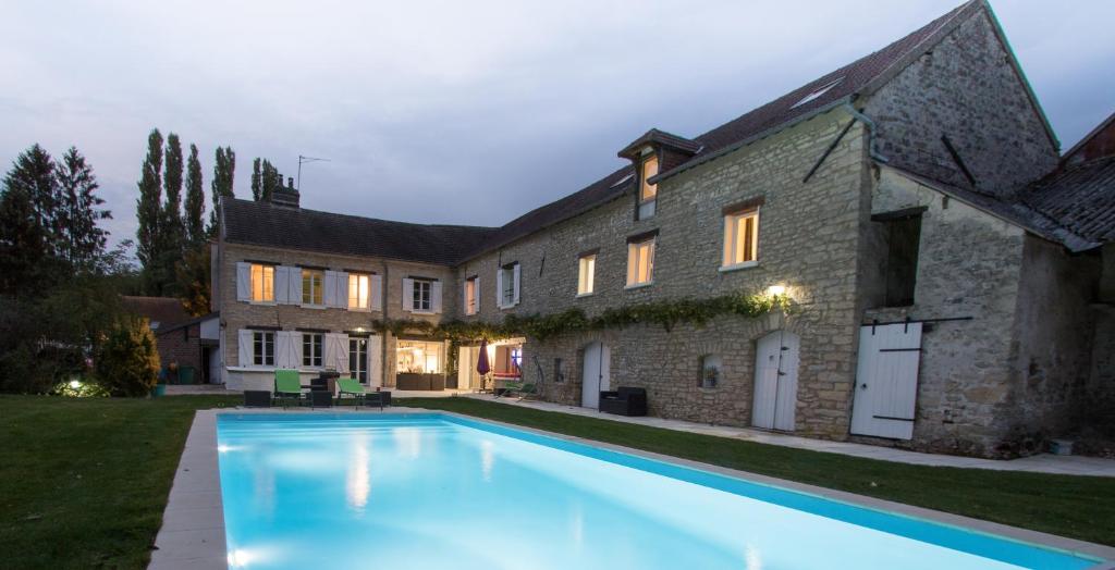 a house with a swimming pool in front of a building at Le clos de Chaussy in Chaussy