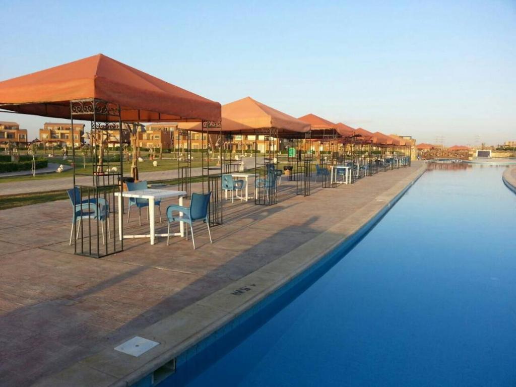 a swimming pool with tables and chairs and umbrellas at Marina wadi degla villa duplex Ain Sokhna in Ain Sokhna