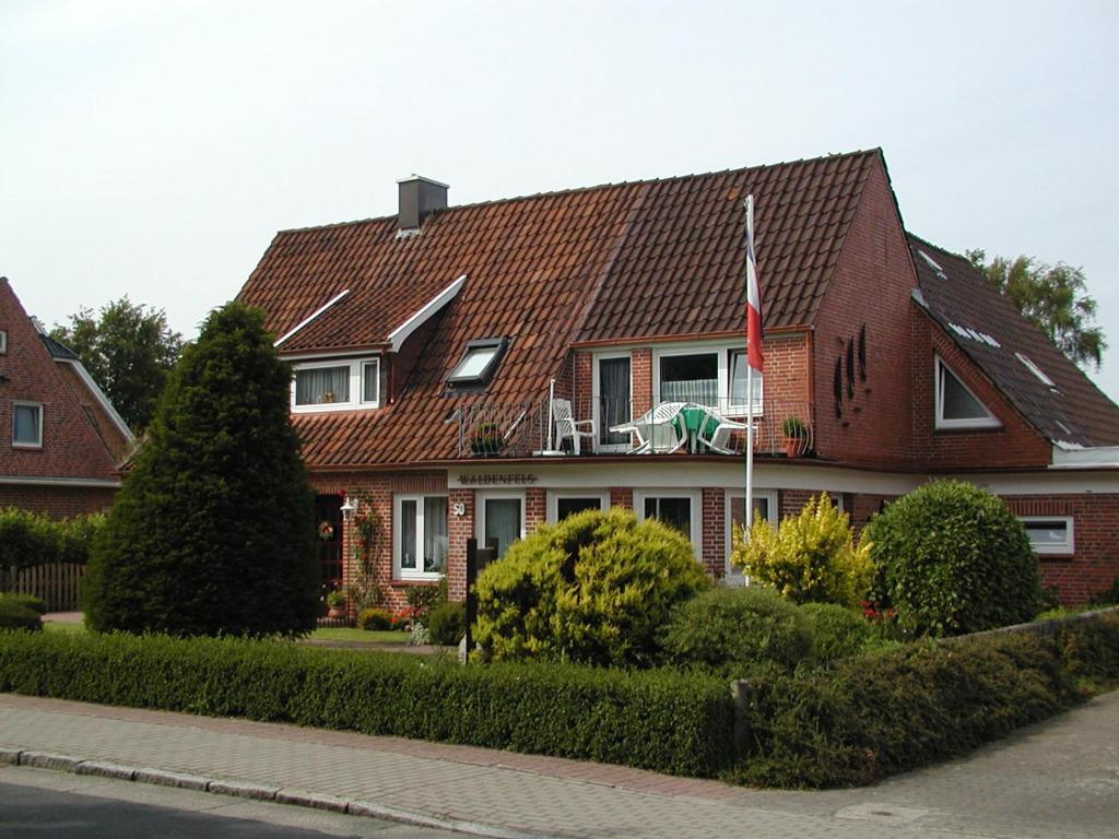 a red brick house with a flag in front of it at Haus Waldenfels in Sankt Peter-Ording
