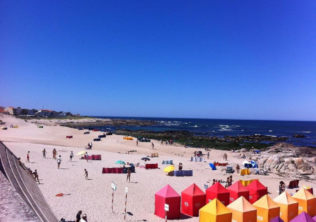 un grupo de personas en una playa con el océano en Trajadinha FêloHouse, en Caminha