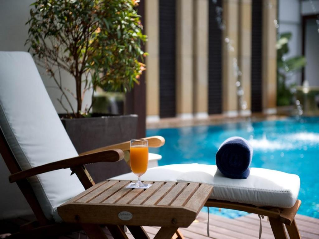 A shaded poolside lounger set up with a drink and rolled towel.