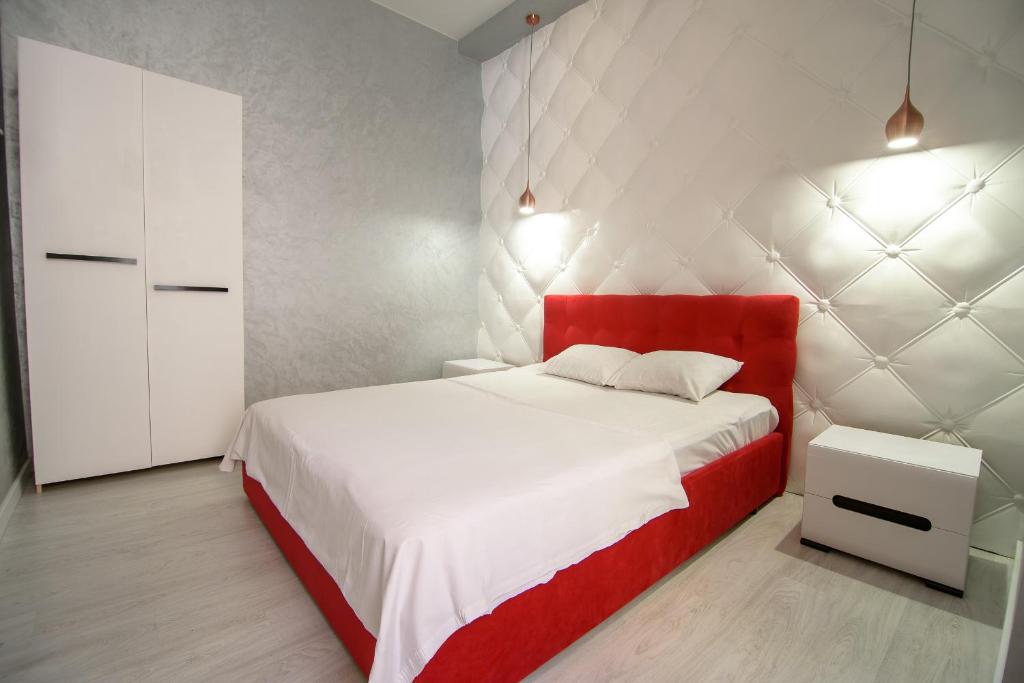 リヴィウにあるNOVA apartmentのベッドルーム(赤と白のベッド1台、キャビネット付)