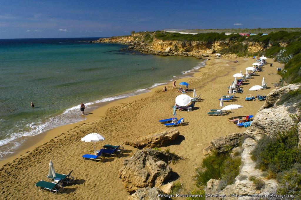a beach with a bunch of chairs and umbrellas at Elisso Apartment in Argostoli