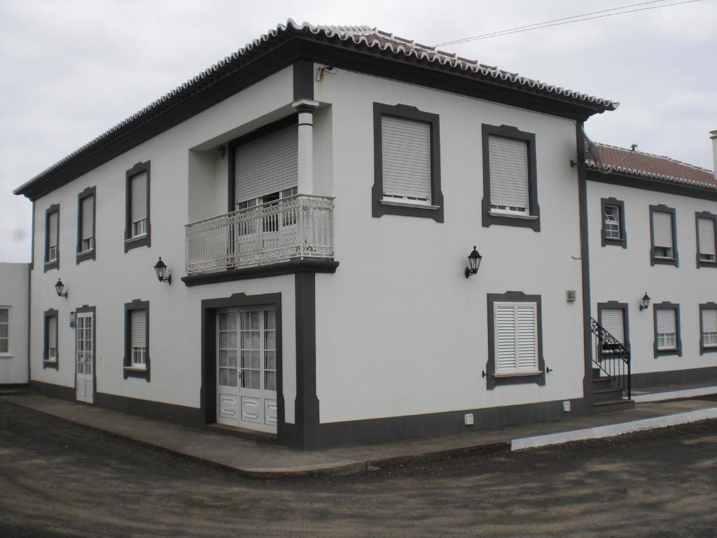 a white building with black shutters and a balcony at Hotel Branco II in Praia da Vitória