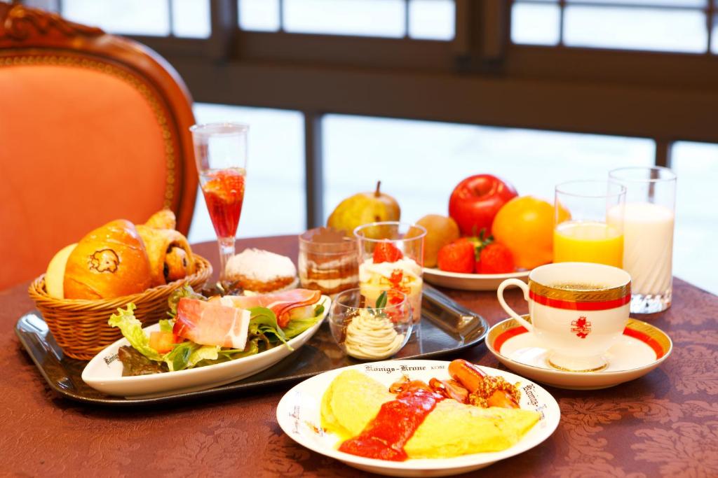 Hotel Konigs-Krone Kobe في كوبه: طاولة مع أطباق من الطعام وأكواب من العصير