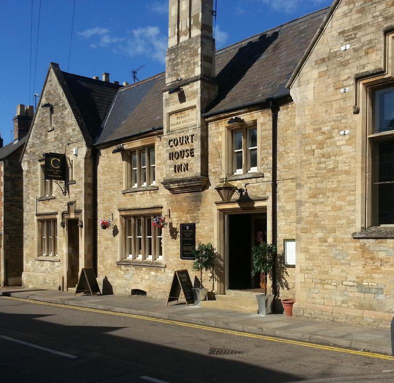 un edificio de piedra con un cartel en la parte delantera en The Court House Inn, en Thrapston