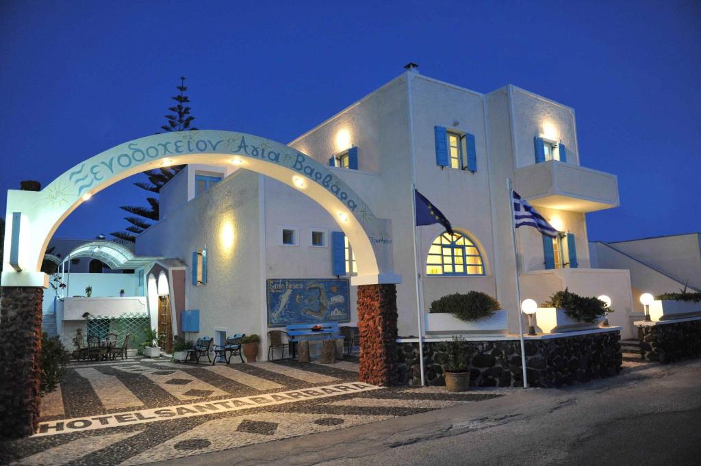 a large white building with an arch at night at Santa Barbara in Perissa