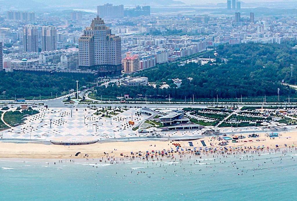 a beach with people on it with a city in the background at PingTan YuCheng Seaview Blue Smart Hotel in Pingtan